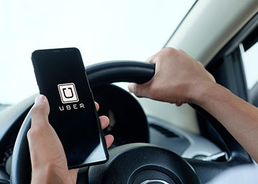 App-based driver laws—Uber driver holding phone, symbolizing November ballot initiative impact.