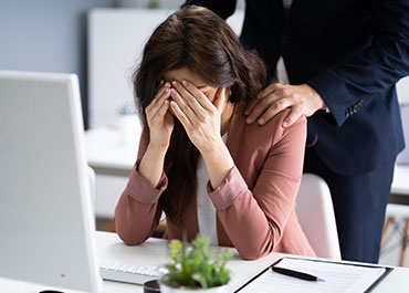 Fearful employee at desk—legal options for workplace sexual harassment by executives.